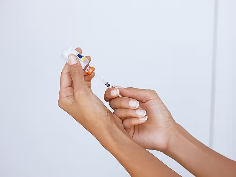 Hands preparing a syringe with medication.