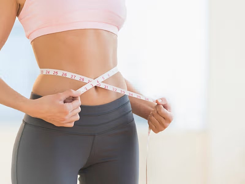 Measuring waist with tape measure on bare skin.