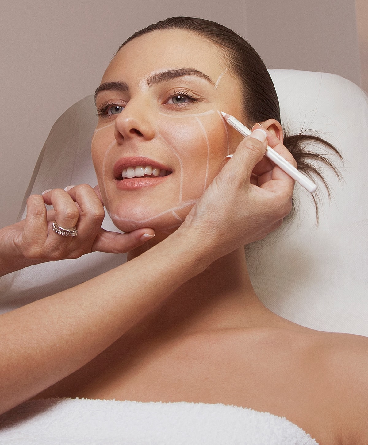 Woman receiving facial treatment with marker lines.