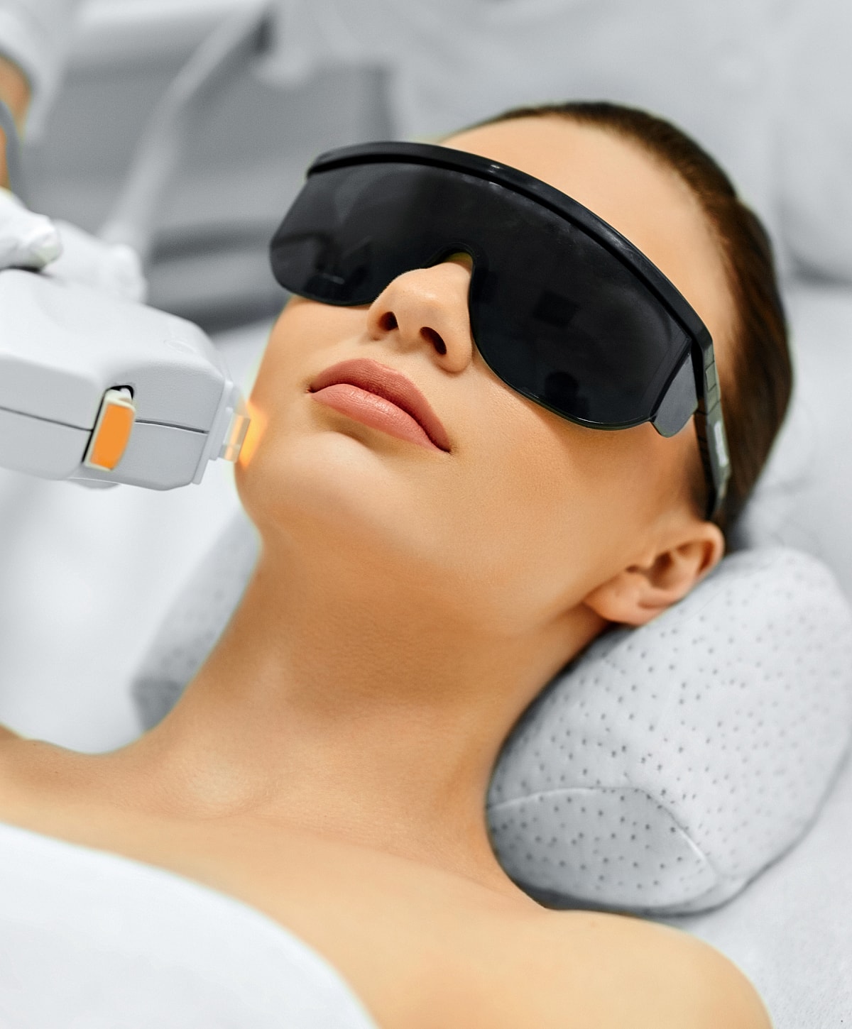 Woman receiving facial treatment with protective glasses.