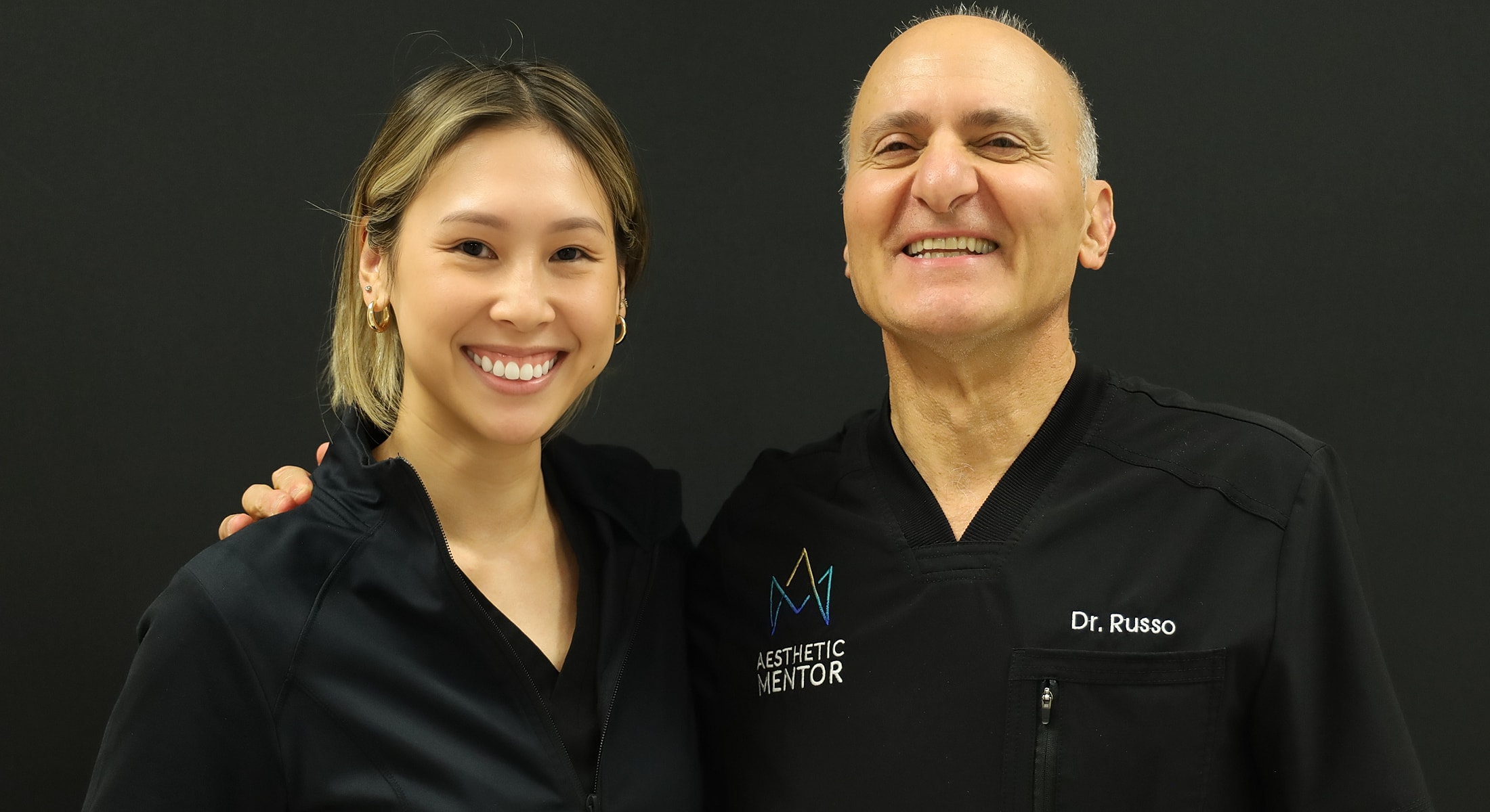 Two smiling professionals in black attire.